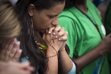 A pilgrim with a rosary wrapped around her hand prays during the World Youth Day closing Mass on Copacabana beach in Rio de Janeiro July 28. Pope Francis celebrated the service with an estimated 3 million people in attendance. (CNS photo/Tyler Orsburn) (July 28, 2013) See WYD-MASS July 28, 2013.